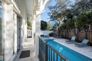 Ein Pool mit Holzterrasse, Liegestühlen und einer überdachten Terrasse.