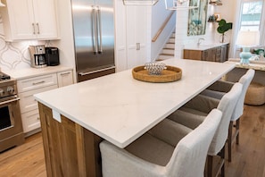 A modern kitchen with stainless steel appliances, a marble countertop, and a central island with chairs. - Private Pool, Steps From Beach- Beach You To It by Royal Destinations (Santa Rosa Beach)