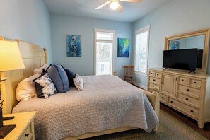 A bedroom with a bed, dresser, television, and artwork on the walls. - Private Pool, Steps From Seaside- Billiken Bungalow by Royal Destinations (Santa Rosa Beach)