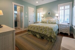 A bedroom with a bed, bedside tables, a dresser, and a door leading to a bathroom. - Private Pool, Steps From Seaside- Billiken Bungalow by Royal Destinations (Santa Rosa Beach)