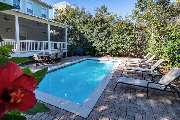 A rectangular swimming pool with a tiled edge, surrounded by a brick patio. There are lounge chairs and a covered seating area with a railing. - Private Pool, Steps From Seaside- Billiken Bungalow by Royal Destinations (Santa Rosa Beach)