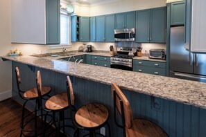 A kitchen with blue cabinets, a granite countertop, a stainless steel refrigerator, and a built-in oven. - Private Pool, Steps From Seaside- Billiken Bungalow by Royal Destinations (Santa Rosa Beach)