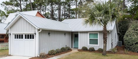 A single-story house with a garage, a green door, and a small front yard.