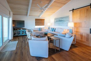 A spacious living room with a large sofa set, a coffee table, and a television. - Gulf & State Park Views, Near Beach Access- Dune Watch by Royal Destinations (Santa Rosa Beach)