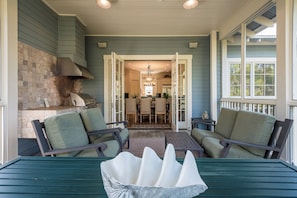 A covered porch with a grill, two chairs, a table, and a view into the house.
