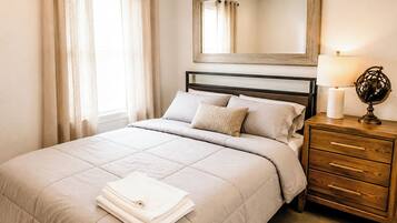 A bedroom with a bed, a nightstand, a lamp, and a mirror.