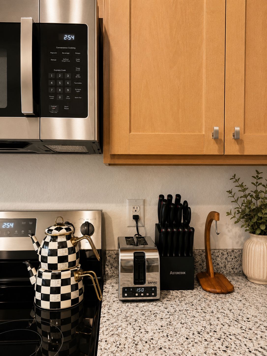 A kitchen with a microwave, toaster, and checkered teapot on the counter.