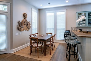 Un coin repas avec une table et des chaises en bois, une cuisine avec des tabourets de bar et un élément décoratif mural.