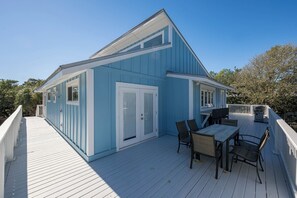 A blue house with a deck, a dining table, and chairs. - Pet Friendly with Private Pool, Near Beach- Gindarra by Royal Destinations (Santa Rosa Beach)