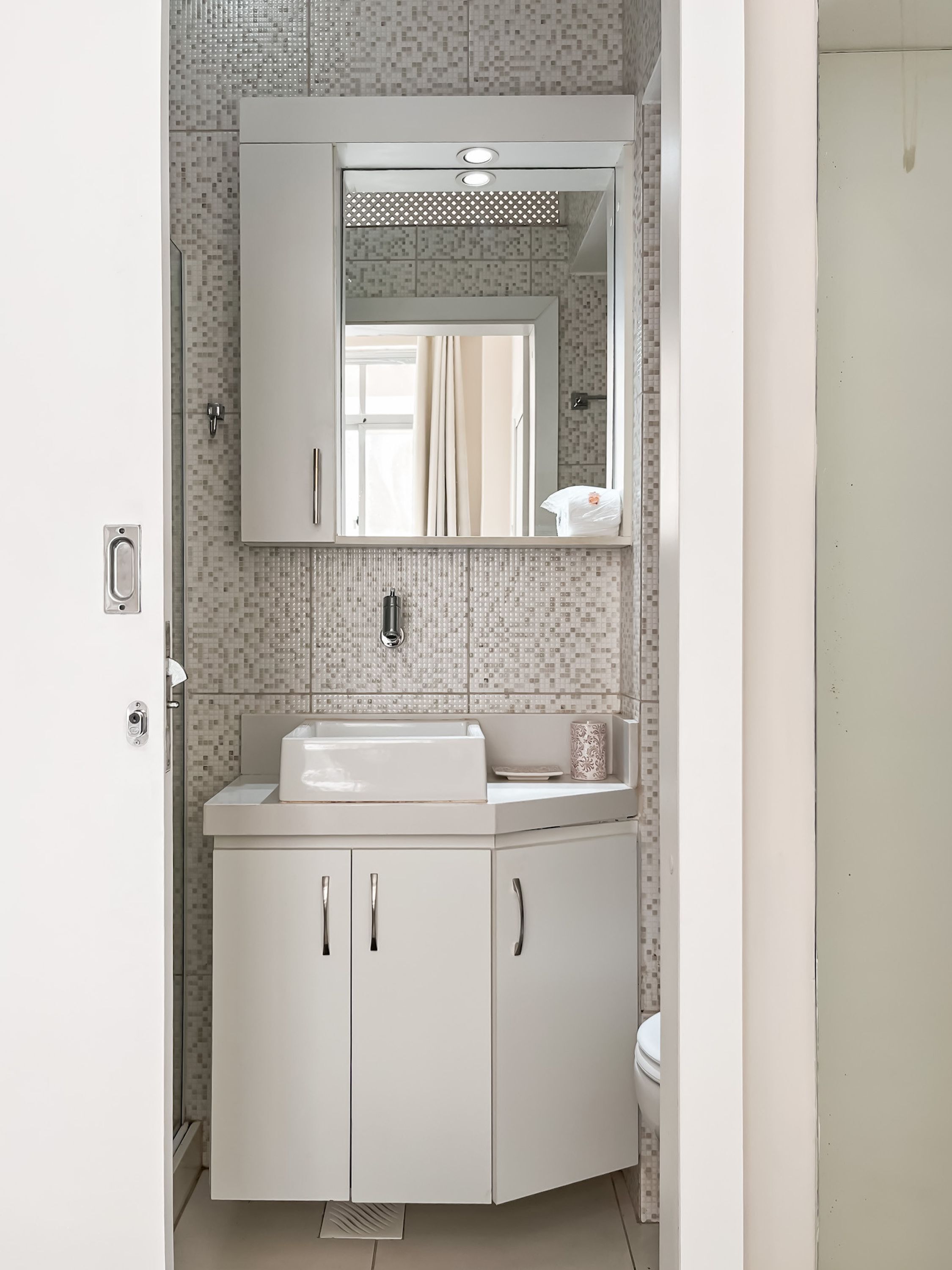 Une salle de bain avec un lavabo blanc, un miroir et des armoires.