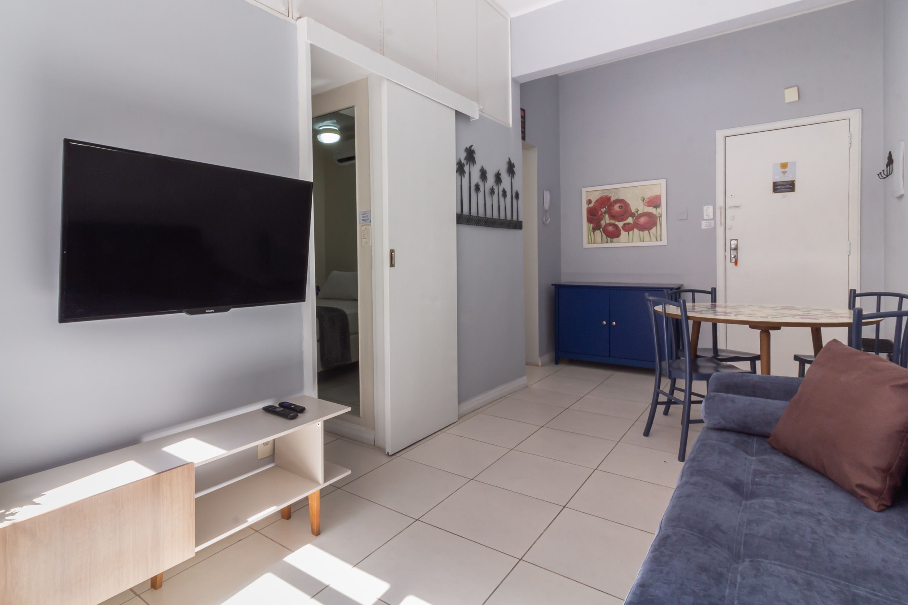 Ein modernes Wohnzimmer mit Flachbildfernseher, einer Couch, einem Couchtisch und einem Essbereich mit Stühlen.
