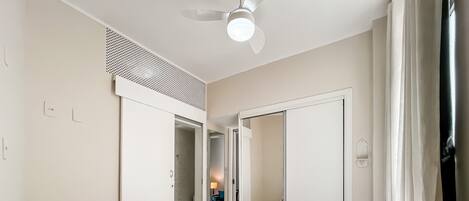 A hotel room with a bed, a ceiling fan, a wardrobe, and a bathroom visible through an open door.