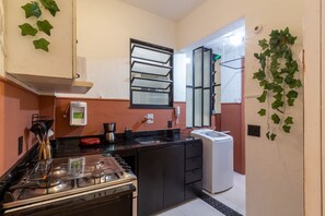 A compact kitchen with a gas stove, a coffee maker, and a small refrigerator. - 2BR Apt Just 7 Mins to Copacabana Beach Br502 (Rio de Janeiro)
