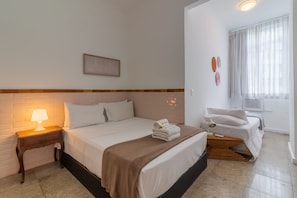 A hotel room with a bed, bedside table, lamp, and a window with curtains. - 2BR Apt Just 7 Mins to Copacabana Beach Br502 (Rio de Janeiro)
