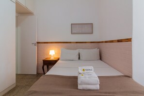 A hotel room with a bed, a nightstand with a lamp, a framed picture on the wall, and a towel with 'PINEAPPLES' on it. - 2BR Apt Just 7 Mins to Copacabana Beach Br502 (Rio de Janeiro)