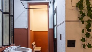 A narrow hallway with a washing machine, a chair, and a hanging light fixture. - 2BR Apt Just 7 Mins to Copacabana Beach Br502 (Rio de Janeiro)