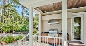A covered outdoor kitchen with a grill, a wooden ceiling, and a view of a forested area. - Private Pool, Walk to Grayton Beach- Grayton Pointe by Royal Destinations (Santa Rosa Beach)