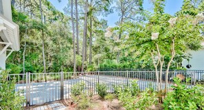 A fenced outdoor area with a paved path, surrounded by trees and greenery. - Private Pool, Walk to Grayton Beach- Grayton Pointe by Royal Destinations (Santa Rosa Beach)