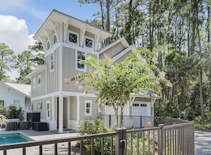 Une maison à deux étages avec une piscine, du mobilier d’extérieur et une cour clôturée.