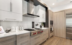 A modern kitchen with stainless steel appliances, wooden cabinets, and a white countertop. - Private Pool, Walk to Grayton Beach- Grayton Pointe by Royal Destinations (Santa Rosa Beach)