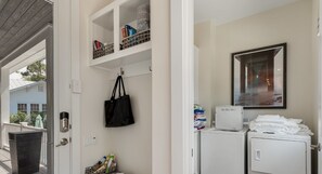 A laundry area with a washing machine, dryer, and shelves with various items. - Private Pool, Walk to Grayton Beach- Grayton Pointe by Royal Destinations (Santa Rosa Beach)