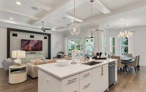 A modern kitchen with a central island, pendant lighting, and a dining area with chairs. - Private Pool, Walk to Grayton Beach- Grayton Pointe by Royal Destinations (Santa Rosa Beach)