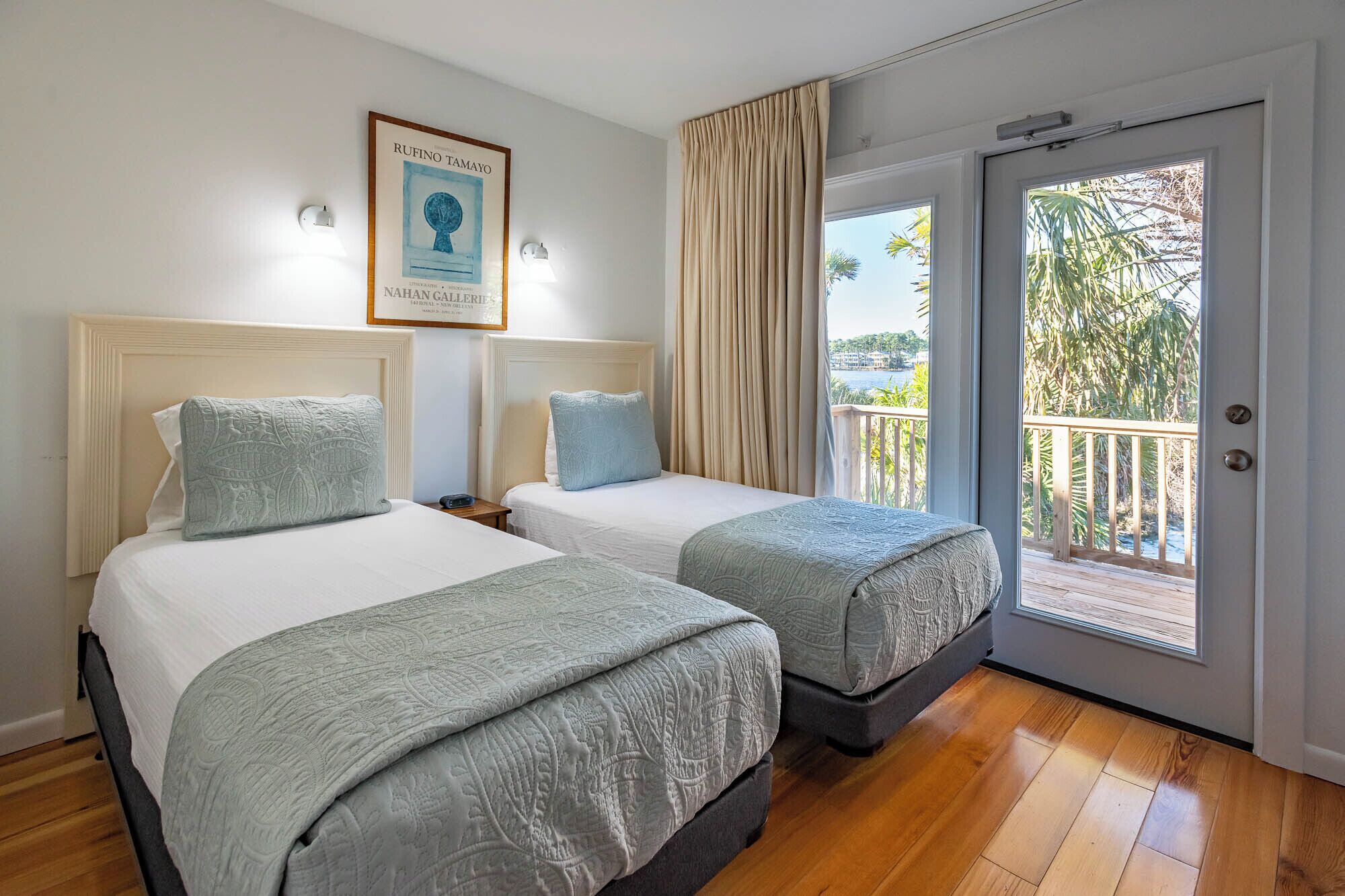A hotel room with two beds, a framed artwork on the wall, and a balcony with a view.