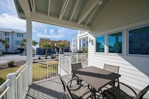 A covered outdoor patio with a table and chairs, a railing, and a view of neighboring buildings. - Gulf Views, Steps From Beach Access- Jada's Dare by Royal Destinations (Santa Rosa Beach)