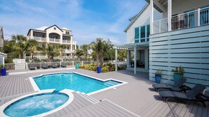Un área de piscina con jacuzzi, sillones de descanso y una terraza de madera.