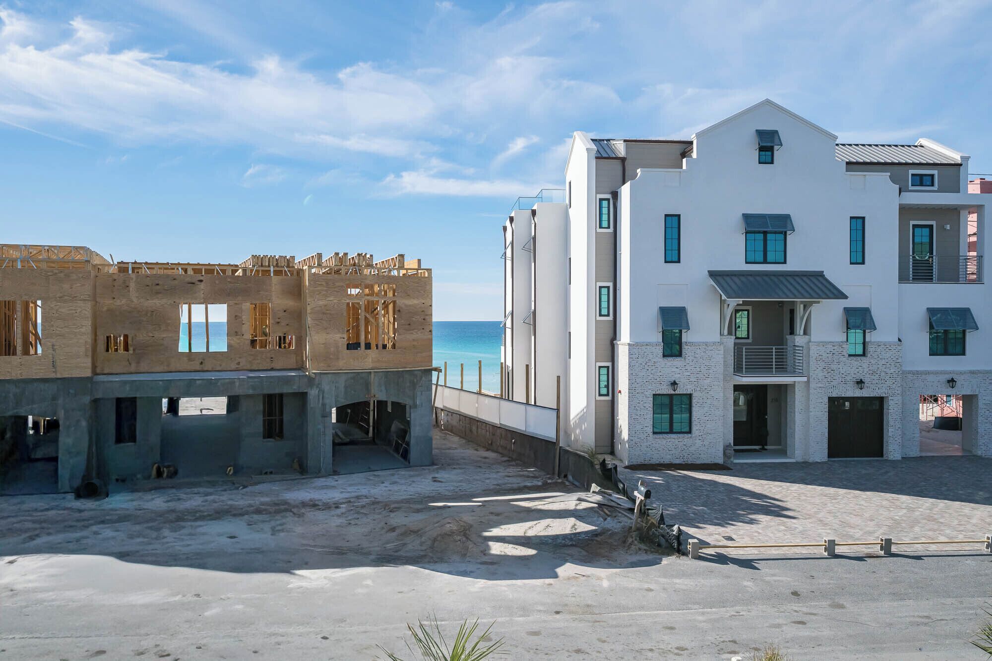 A beachfront property with a partially constructed building and a completed white building with multiple windows and balconies.