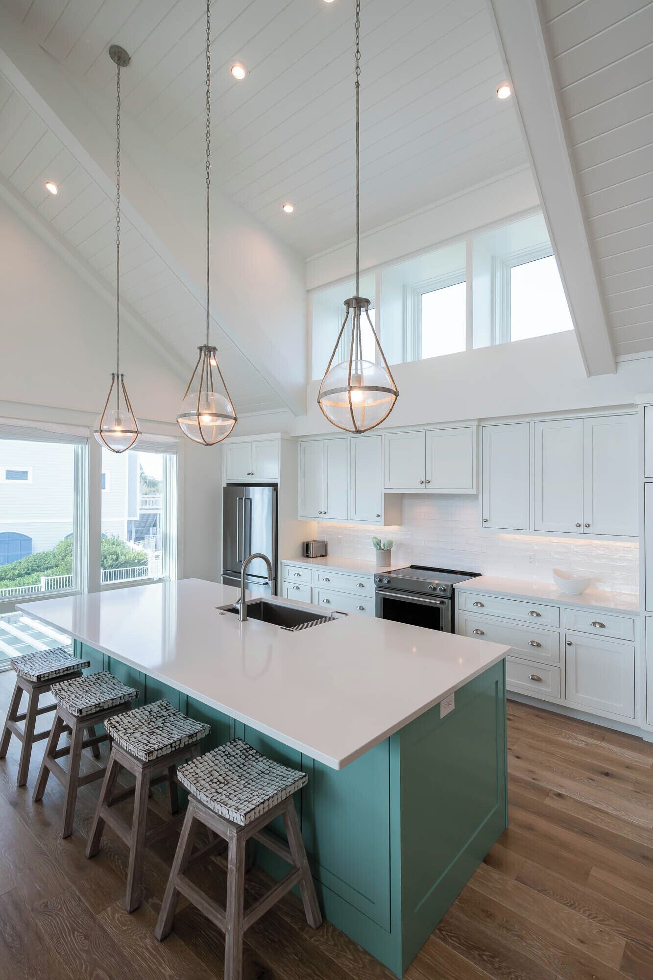 A modern kitchen with a large island, bar stools, and pendant lighting.