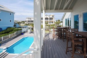 A poolside area with a wooden deck, lounge chairs, and a view of neighboring buildings. - Gulf Views, Steps From Beach Access- Jada's Dare by Royal Destinations (Santa Rosa Beach)