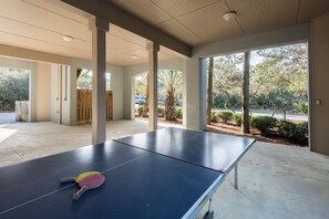 A ping pong table with paddles in a covered outdoor area with large windows and a view of trees. - Private Pool, Near Beach & State Park- Lucky Dog by Royal Destinations (Santa Rosa Beach)