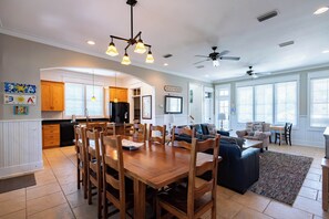 A spacious living area with a dining table, sofas, and a kitchen in the background. - Private Pool, Near Beach & State Park- Lucky Dog by Royal Destinations (Santa Rosa Beach)