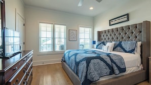 A bedroom with a large bed, a dresser, and a ceiling fan.