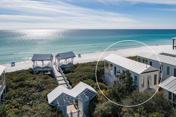 Ein an der Küste gelegenes Anwesen mit mehreren Gebäuden, einer Holzterrasse und Blick auf den Strand.
