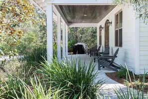 A covered porch with a grill, two Adirondack chairs, and a pathway leading to a building. - Private Pool, Short Walk to Beach- Milly Mae's Cottage by Royal Destinations (Santa Rosa Beach)