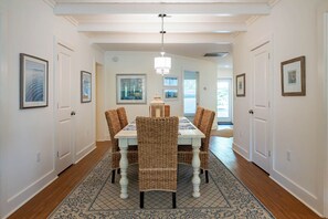 A dining area with a white table, wicker chairs, and a patterned rug. - Across From Beach, Steps From Seaside- Mimi's Cottage by Royal Destinations (Santa Rosa Beach)
