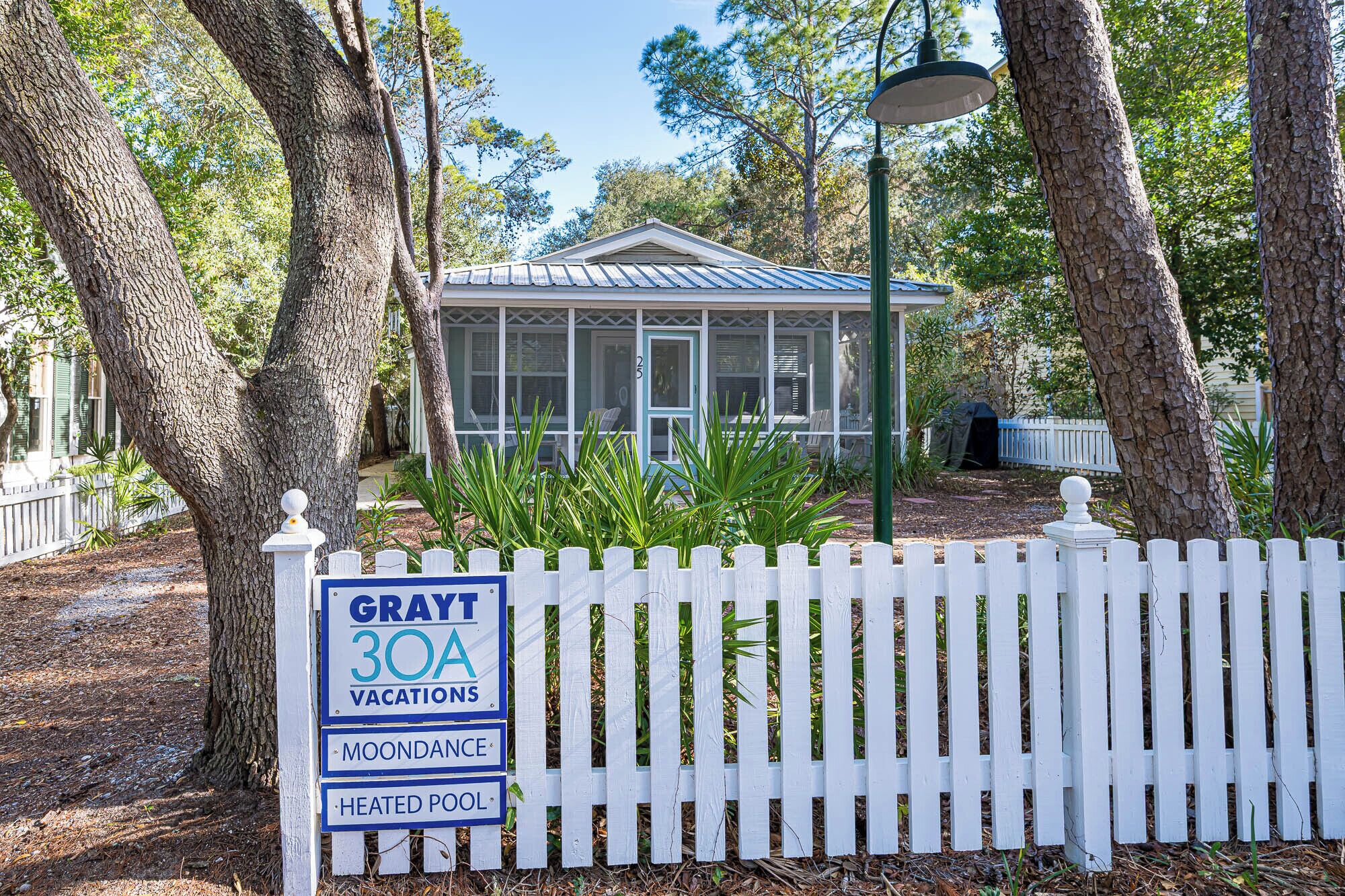 Une maison de vacances appelée « Grayt 30A », dotée d’une véranda grillagée, d’une fenêtre grillagée et d’une clôture blanche en bois.