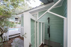 A covered outdoor shower area with a hose and showerhead, adjacent to a swimming pool. - Pet Friendly with Pool, Near Beach & Seaside- Moondance by Royal Destinations (Santa Rosa Beach)