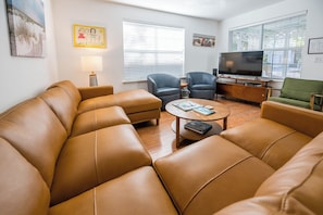 A living room with a sectional sofa, two armchairs, a coffee table, a TV, and artwork on the walls. - Pet Friendly with Pool, Near Beach & Seaside- Moondance by Royal Destinations (Santa Rosa Beach)