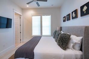 A bedroom with a bed, a ceiling fan, a TV, and framed artwork on the wall. - Private Pool, Steps From Beach Access- Ocho Cinco by Royal Destinations (Santa Rosa Beach)