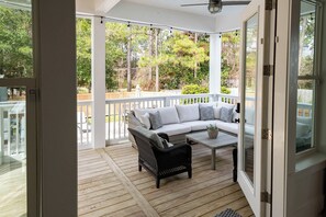 A covered porch with a white railing, a sectional sofa, a coffee table, and a wicker chair. - Private Pool, Steps From Beach Access- Ocho Cinco by Royal Destinations (Santa Rosa Beach)