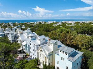 A coastal residential area with multiple two-story houses, some with balconies, and a clear view of the ocean.