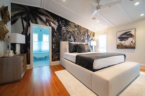 A bedroom with a bed, a nightstand, a wall mural, a ceiling fan, and a window.