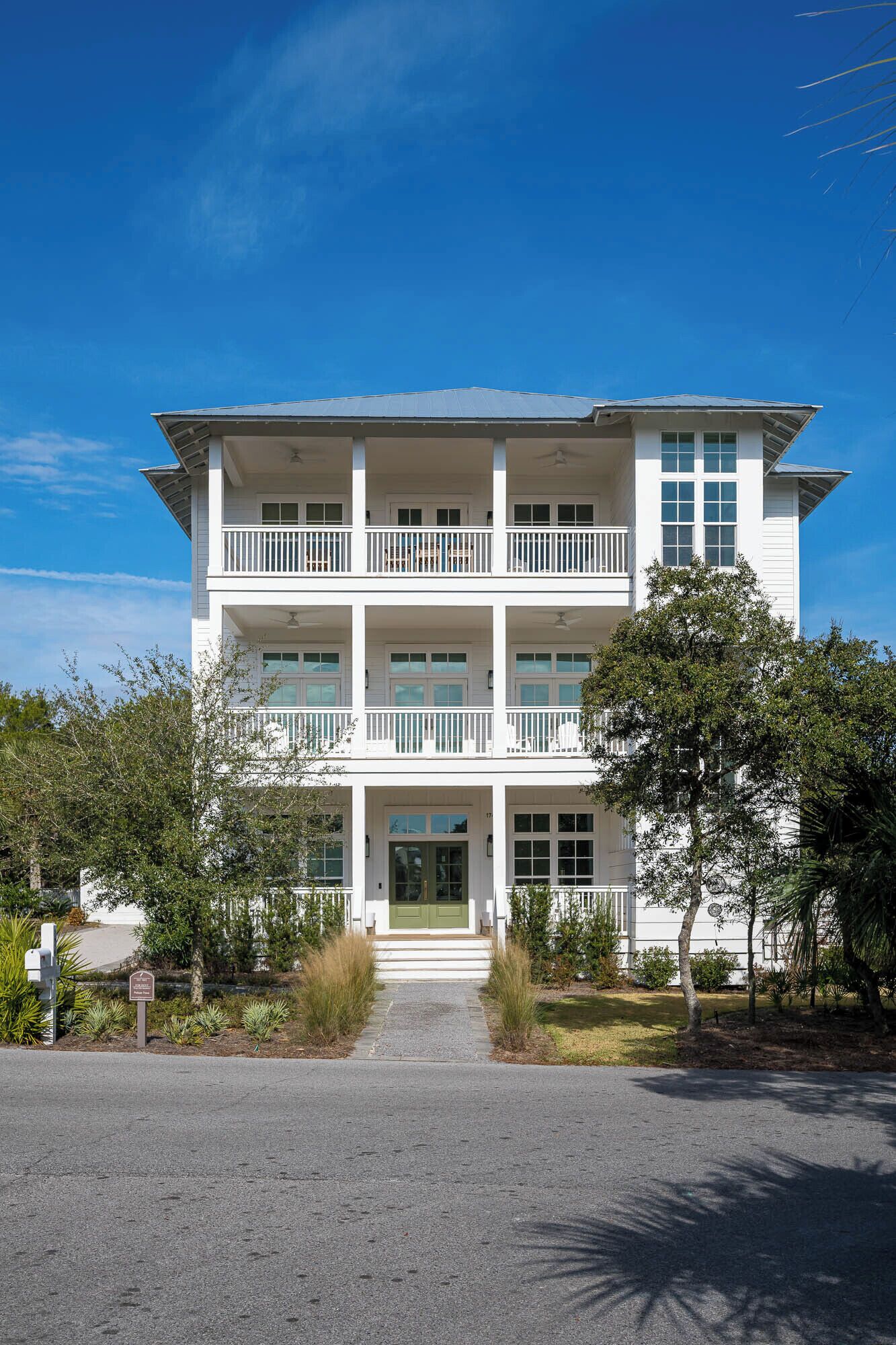 A two-story building with a central entrance, a balcony on the second floor, and a clear sky.