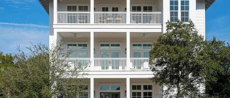A two-story building with a central entrance, a balcony on the second floor, and a clear sky.