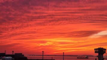 A sunset over a harbor with a bridge and buildings in the foreground.