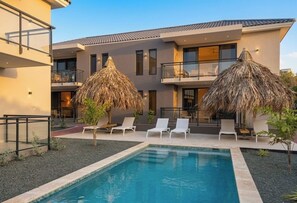 A modern hotel with a swimming pool, lounge chairs, and thatched umbrellas. - newly build 12 Luxury 2BR/2BA apartments on gated resort with pool, ideally located near Mambo Beach & Jan Thiel. Fully equipped kitchen, AC in all rooms, private balcony. Perfect for a comfortable and relaxing stay in Curaçao. (Willemstad)