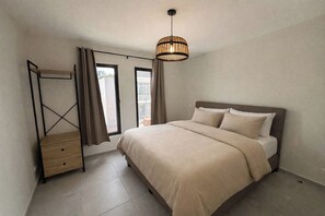 A bedroom with a bed, a bedside table, a hanging light fixture, and a window with curtains. - newly build 12 Luxury 2BR/2BA apartments on gated resort with pool, ideally located near Mambo Beach & Jan Thiel. Fully equipped kitchen, AC in all rooms, private balcony. Perfect for a comfortable and relaxing stay in Curaçao. (Willemstad)